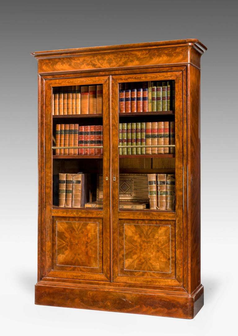 A very fine quality 19th century walnut bookcase or china cabinet, the top section of pronounced form, the stiles quartered in fine timbers with matching veneers to the bottom section. The whole of the best quality.

