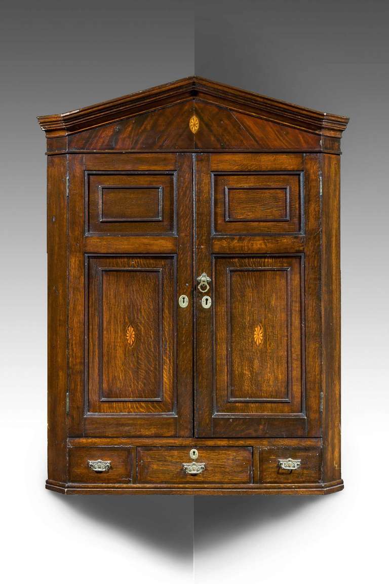 An attractive north country hanging corner cupboard, probably Lancashire, the main body with inlaid applications to the door, the top pediment which is original of finely figured flame mahogany with good and original interior, the bottom section