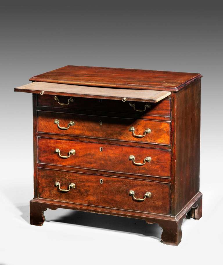 A small George III period mahogany Chest of Drawers, the top with a moulded edge over a dressing slide, period swan neck handles and shaped bracket feet.