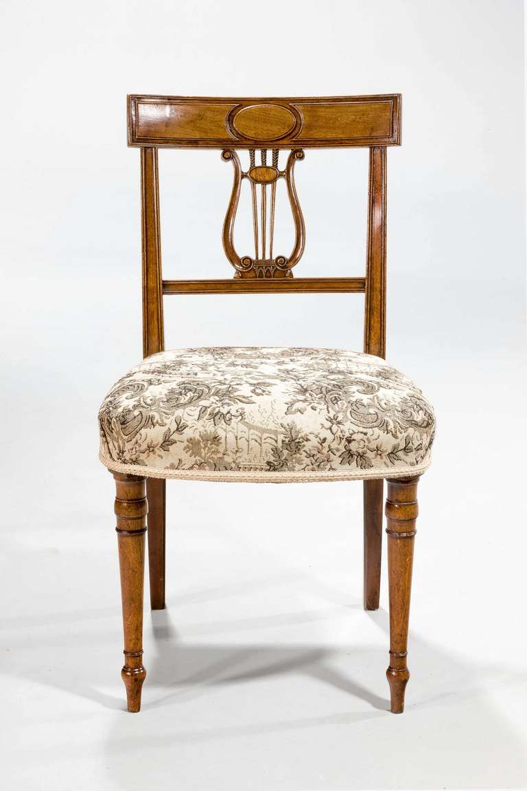 A good set of four George III period mahogany single dining chairs with a sophisticated design to the back splat in the form of a stylized harp and on finely turned circular supports.