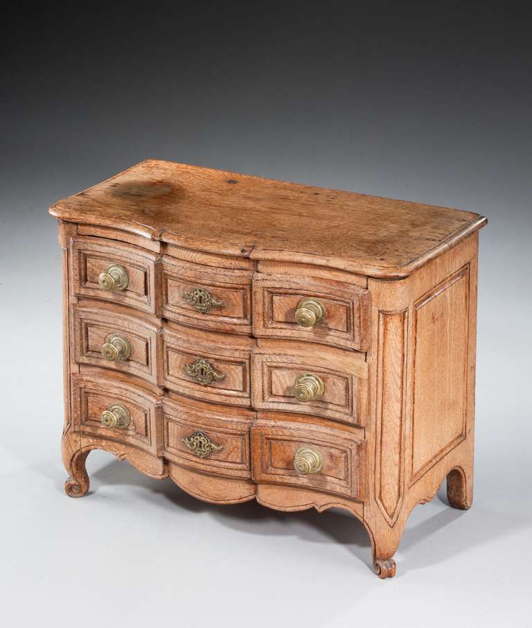 19th century continental oak serpentine fronted miniature bombe commode, standing on a French scroll foot.