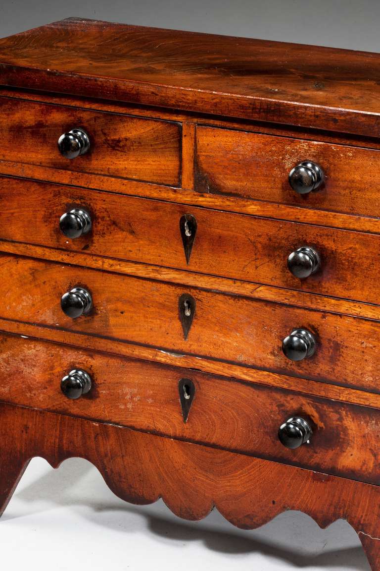 Late George III period mahogany miniature chest of drawers with shaped apron.