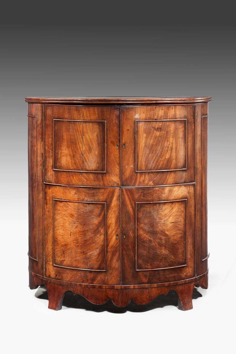 A well figured late George III mahogany bow-front commode of exceptional color and patina swept and shaped apron on flared bracket supports.

RR.