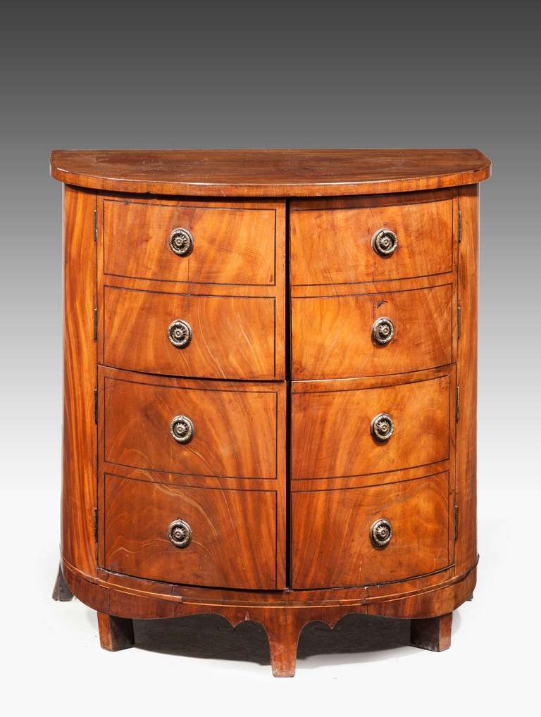 A well figured late George III period mahogany bow-fronted commode, swept and shaped apron on flared bracket supports.

