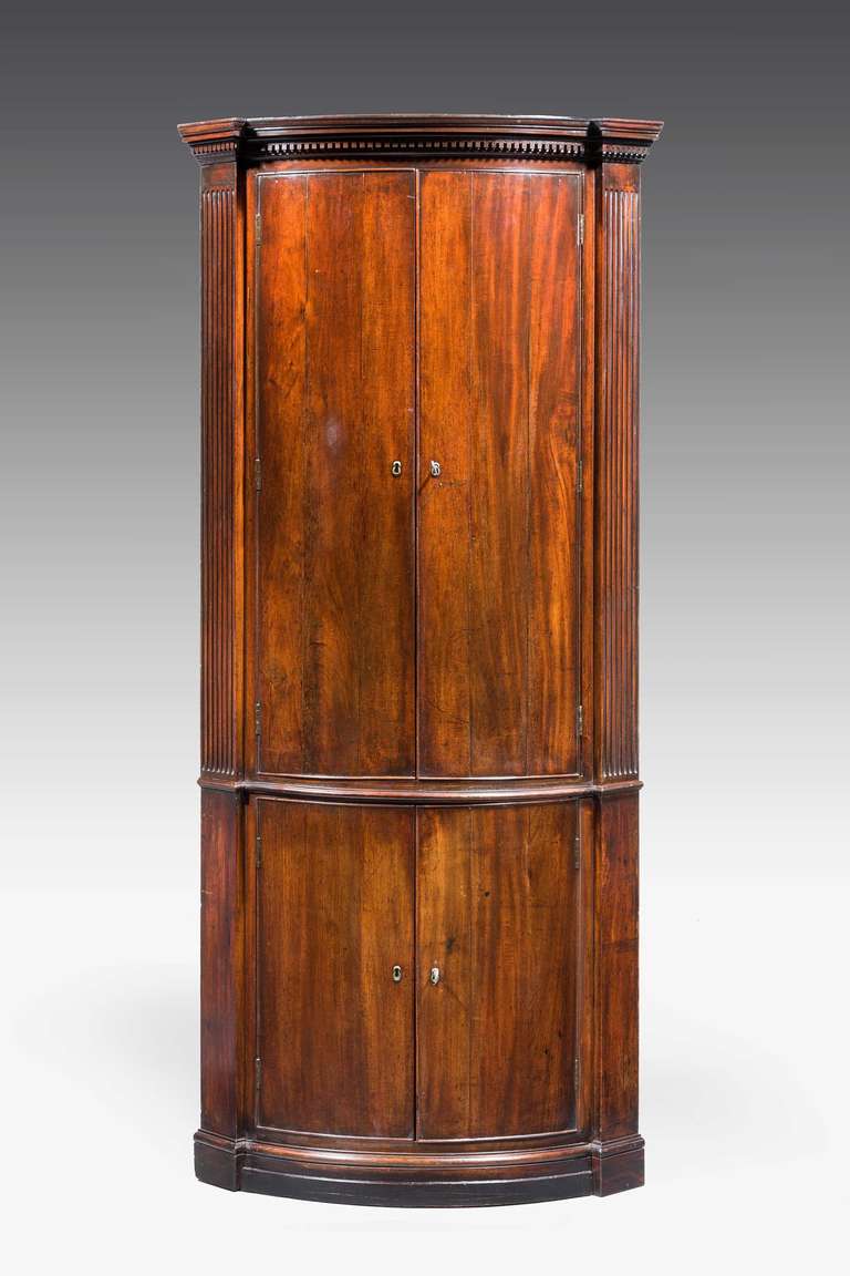 An unusual George III period bow front mahogany double Corner Cupboard, the doors with applied slender outer frame, the supports with reeded decoration, key moulding to the upper section.

RR