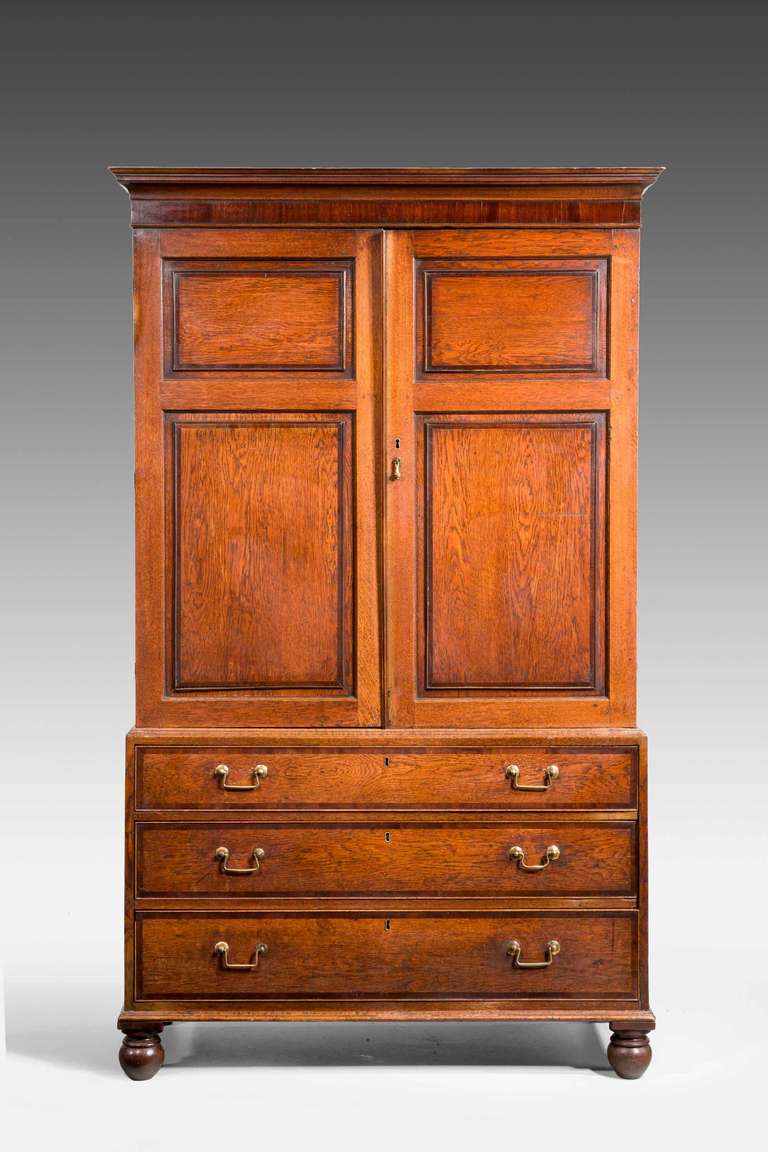 A most unusual late George III period oak press, the highly figured timbers with fielded panels, the interior with three original shelves, good square section period brass handles on original turned supports. Most unusual to find a press in oak with