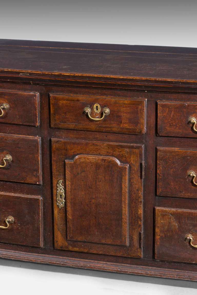 Good George III period oak dresser base with seven drawers and a central cupboard, the door with a raised panel and crossbanding, excellent color and patina

A Welsh Dresser sometimes known as a kitchen dresser or pewter cupboard, is a piece of