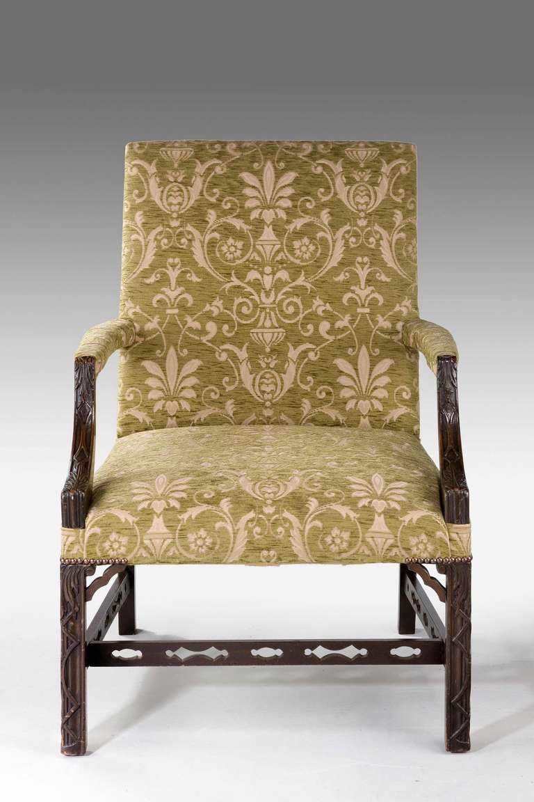 A mahogany framed 'Gainsborough' chair showing Chinese Chippendale influence, the arms and supports with finely executed blind fret carving joined by pierced cross stretchers.

RR.