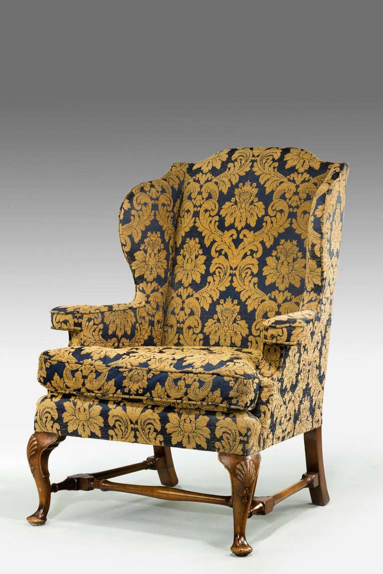 An attractive 19th century walnut framed wing chair of early 18th century design. Well pronounced and well-shaped wing with cabriole supports and stretchers

Provenance
An 18th or 19th century wing chair is an easy chair or club chair with