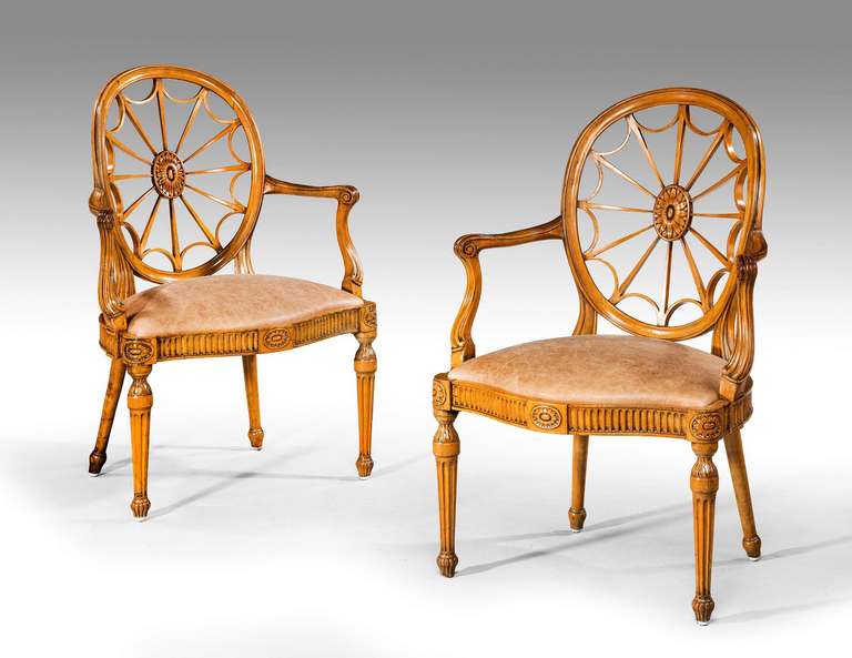 A pair of very elegant 18th century style satin beech elbow chairs, the back splats of a wheel design radiating from the well carved central paterae. The serpentine front rails arcaded with a central motif, the motive repeated on the both ends and
