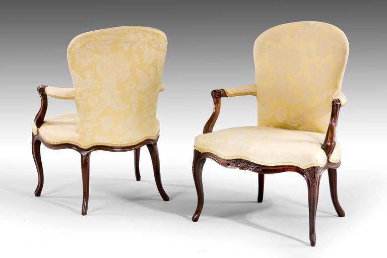 Pair of George III period mahogany frame chairs in the 'French' taste, the swept arm supports with incised carving, serpentine front and side rails with foliage and scroll detail. The supports with graduated hairbells. Two others pairs available.

