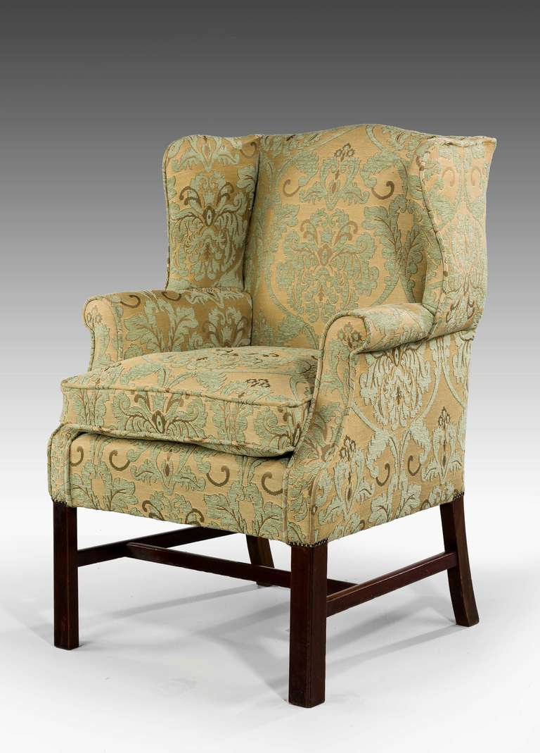 A mahogany framed wing chair of George III style. Strong square chamford supports joined by a 