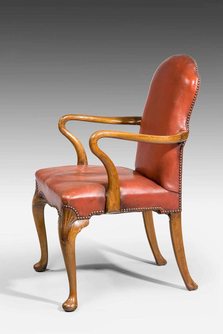 A walnut and leather desk chair with shepherd crook arms over carved cabriole supports ending in pad feet.

RR.