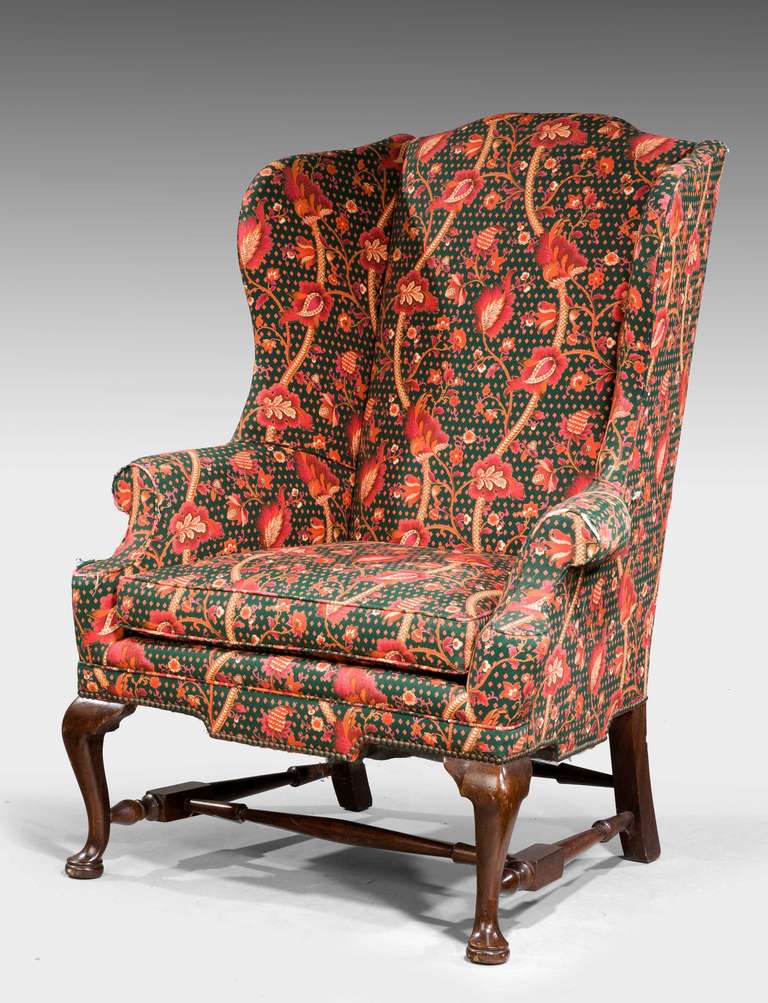 George I design walnut framed wing chair, cabriole supports terminating on pad feet with well turned cross stretcher.

Provenance:
An 18th or 19th century wing chair is an easy chair or club chair with 
