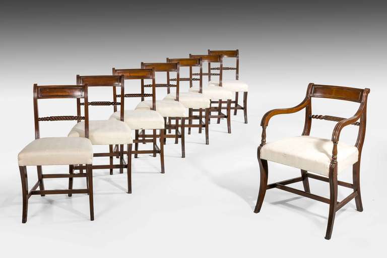 Set of eight (seven side and one carver) Regency period mahogany framed sabre leg dining chairs (five circa 1805 and three circa 1890). The backs with shaped 'Trafalgar' rope twist sections, the supports reeded with H-cross stretchers.

RR.