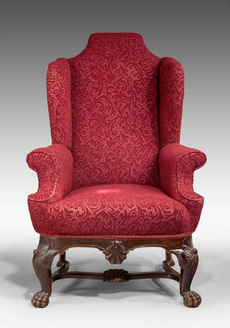 A late 19th century substantial and finely carved mahogany wing chair of early George III design, the supports with conch shells over finely executed hairy paw feet, Irish.

Provenance
An 18th or 19th century wing chair is an easy chair or club