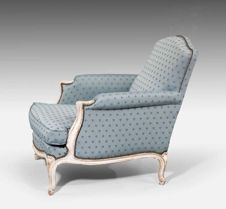 A pair of 19th century Louis XV design painted beech fauteuils, the ivory ground paintwork now slightly tired, covered in French linen fabric with fleur de lis design.

