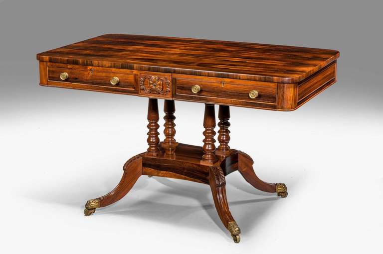 A fine Regency period centre standing table, the timbers of quite exceptional quality and figuring, the frieze incorporating two drawers the reverse with dummy drawers, the top supported on four finely turned balusters, over a rectangular section
