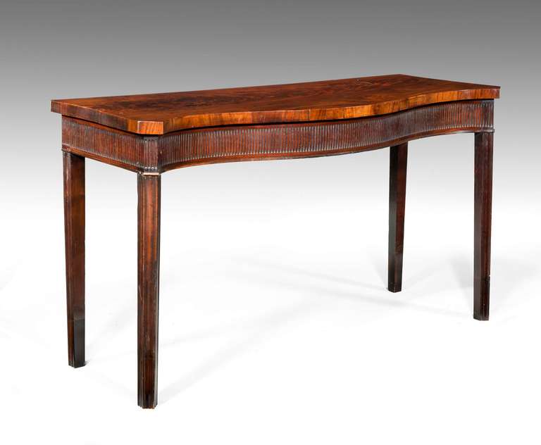 An exceptionally finely figured George III period mahogany serpentine console table, the cross banded top edge over a finely carved arcaded freeze, square section chamfered supports.

RR.