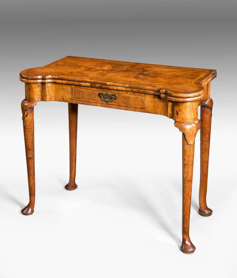 Queen Anne period walnut Games Table with a shaped top with cross banding and herringbone inlay and cushion top moulds, baize fitted interior with guinea moulds and corner recess for candles