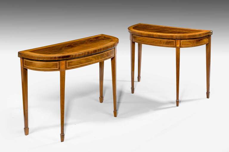 Sheraton period, a fine pair of George III period mahogany ‘D’ shaped card tables, the finely figured mahogany tops with broad satinwood crossbanding, ebony line inlay supported on square section supports terminating in banded spade feet.

