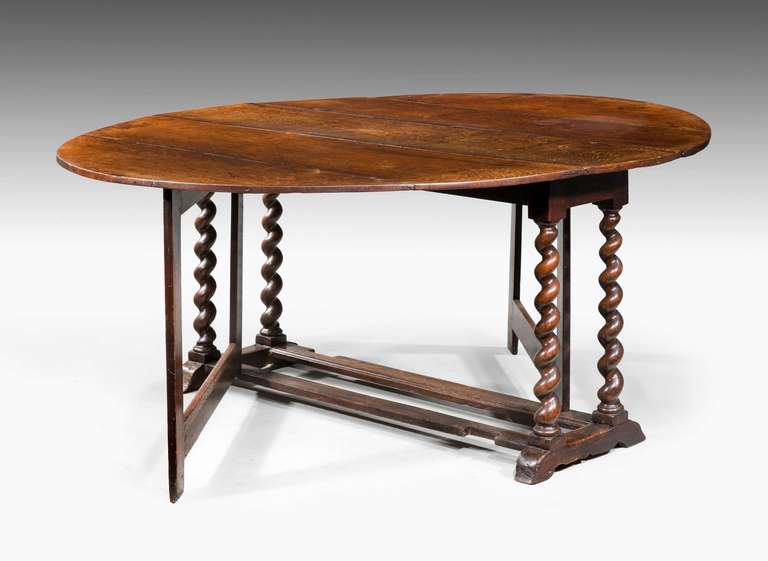 A William and Mary period oak large gate leg table with the two leaves virtually touching the floor on spiral supports with square section legs.

  