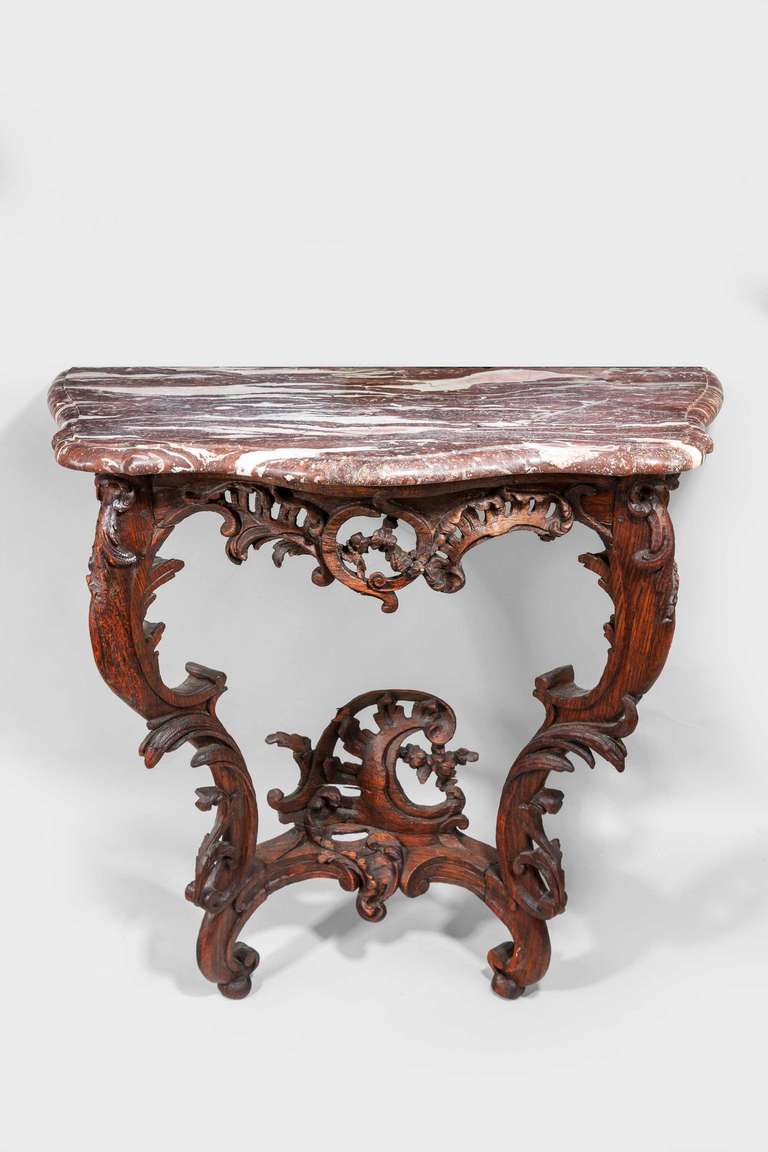 A good mid-18th century oak pier table of very small proportions, the two flowing supports elaborately carved with leaves and foliage, the tops delicately pierced matching a scroll section emanating from within the feet, brown marble period top.

