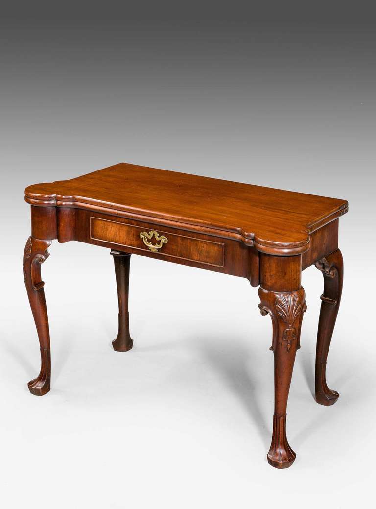 Une belle table de jeu du milieu du 18ème siècle en acajou très figuré, la façade concave incorporant un tiroir avec une belle plaque en laiton d'époque, les genoux avec des volutes et des supports cabriole à coquilles finement sculptés se terminant