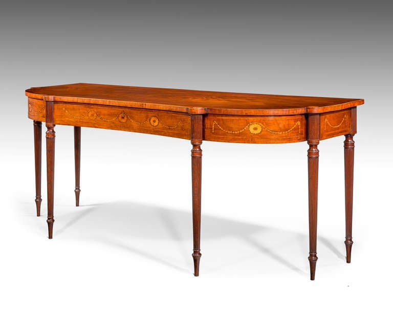 A fine and elegant George III period serving table of bow breakfront and concave design, the top with a stylized marquetry sunburst decoration, the freeze again with harebell swags in boxwood and contrasting timbers. Exceptionally fine turned and
