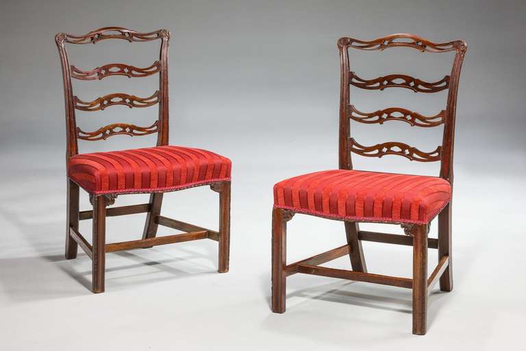 Pair of Chippendale period mahogany framed wavy ladderback side chairs, the top rails with well carved scrolls, four horizontal splats shaped and pierced, serpentine framed seats with egg and dart moulding.

RR.