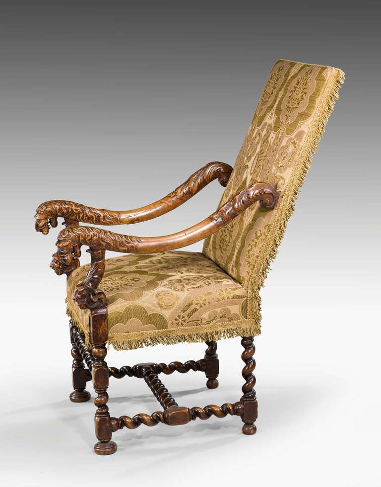 A late 17th century walnut armchair with writhen supports and stretchers, the arms terminating in vigorously carved masks. Currently upholstered in exceptionally fine antique fabric.

