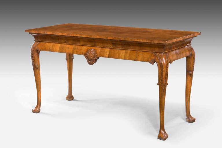 A walnut center standing table of George I design, the main edge of entirely very well figured timbers, the knees carved with anthemion over slightly sectioned pad feet, the carcass entirely adzed from the solid, early 20th century.

RR.