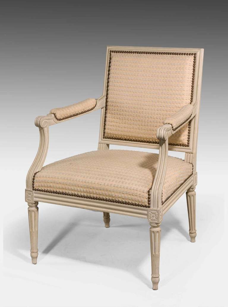 Pair of ivory ground color elbow chairs of Louis XVI design, made early 20th century.