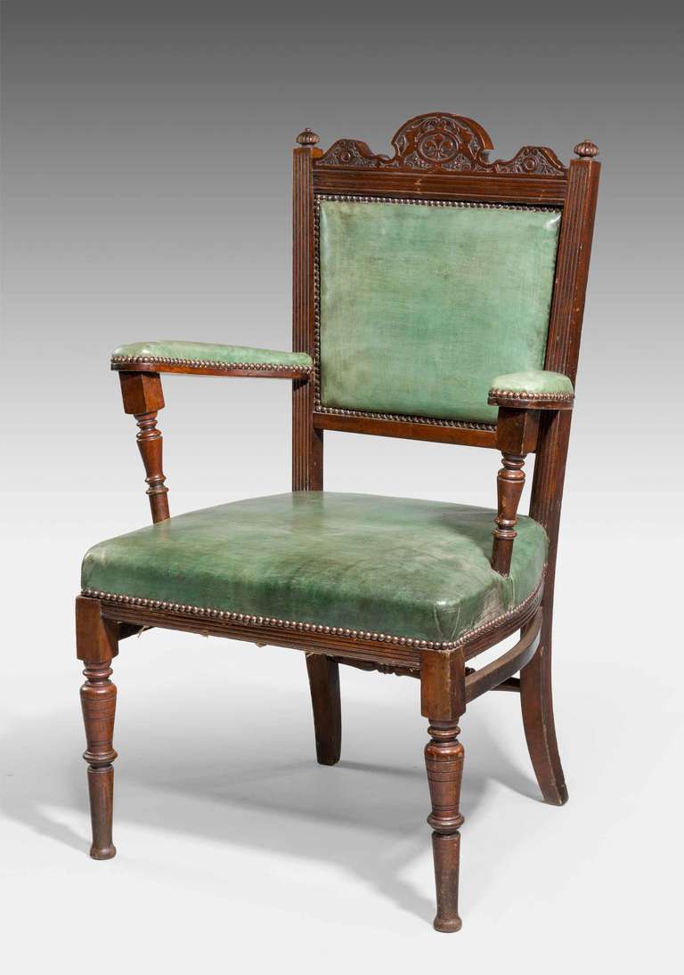 Late 19th Century mahogany framed Elbow Chair with strongly flared arms and turned supports. The upper back carved with 'fleur de lis' and foliage.