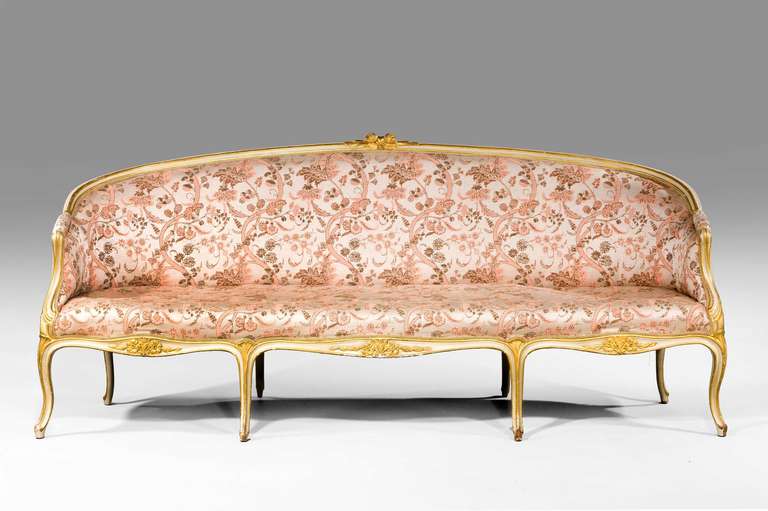 A fine George III period giltwood sofa in the French taste, the continuously flowing triple serpentine front rails carved with flowers over French style cabriole supports.

