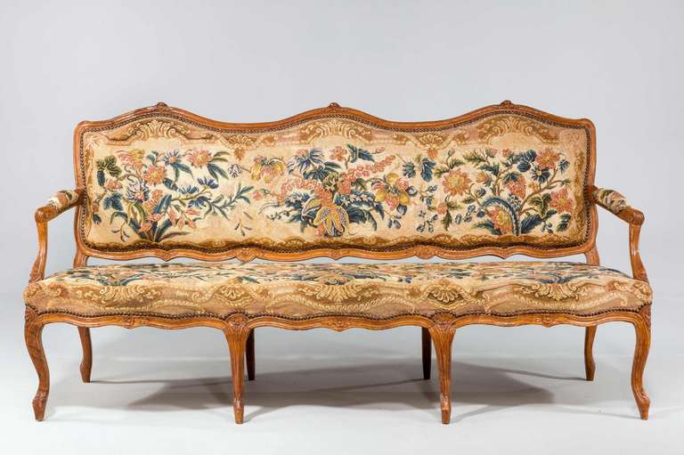 Louis XV period beech frame sofa, the multi serpentine shaped fronts well carved with floral emblems upholstered in a good 19th century tapestry specially woven.

