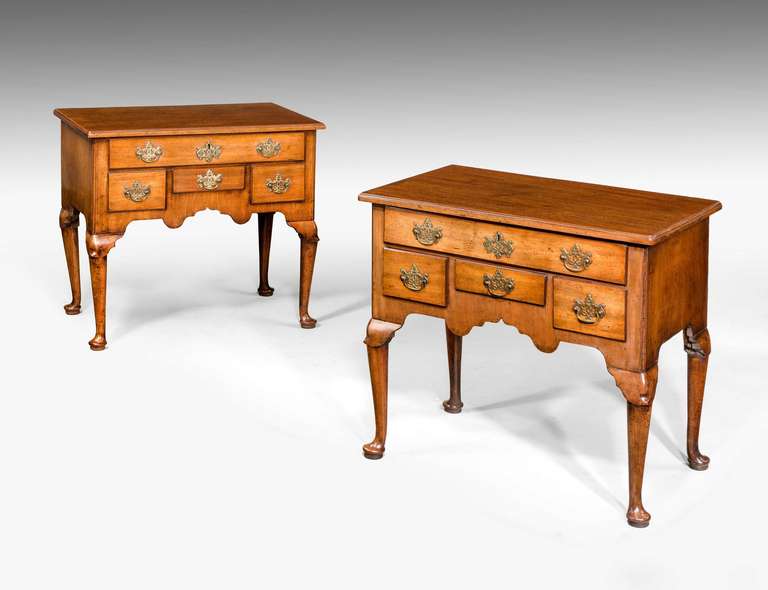 An exceptionally rare pair of George II period mahogany lowboys, the moulded tops over five graduated drawers with cabriole supports, and the knees surmounted with lappets.

RR.