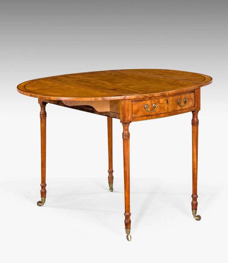 Ein feiner ovaler Pembroke-Tisch aus satiniertem Holz mit quer verlaufenden und gestreiften Kanten auf sehr feinen, sich verjüngenden Stützen mit gedrechselten Abschnitten.

RR.