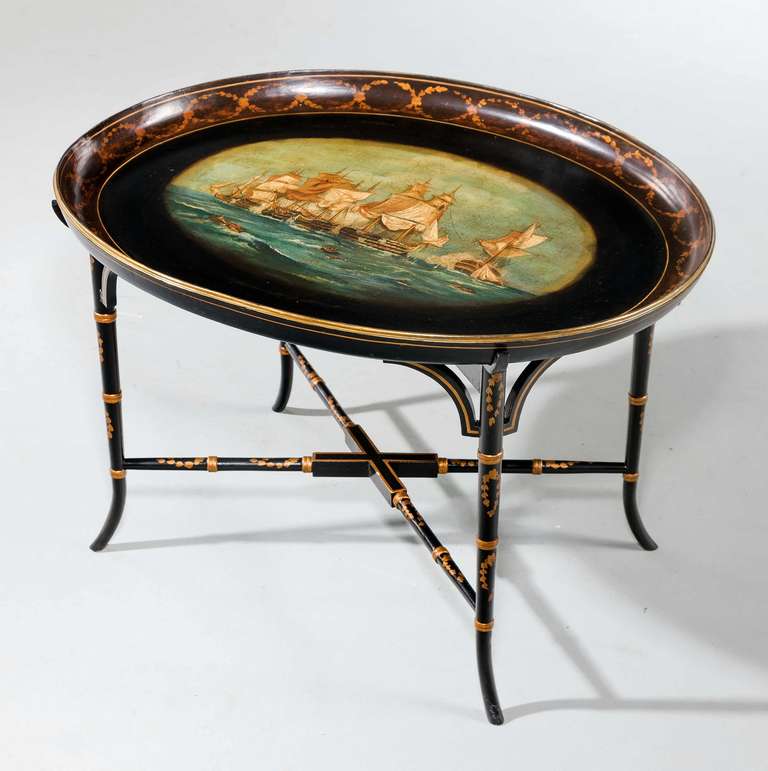 A well painted mid-19th century papier mache oval tray, the dished edge with finely gilded laurel decoration, the oil painted main panel depicting ‘Men of War’ in the 17th century style. On a modern base in black and gilt decoration. Signed Deanes