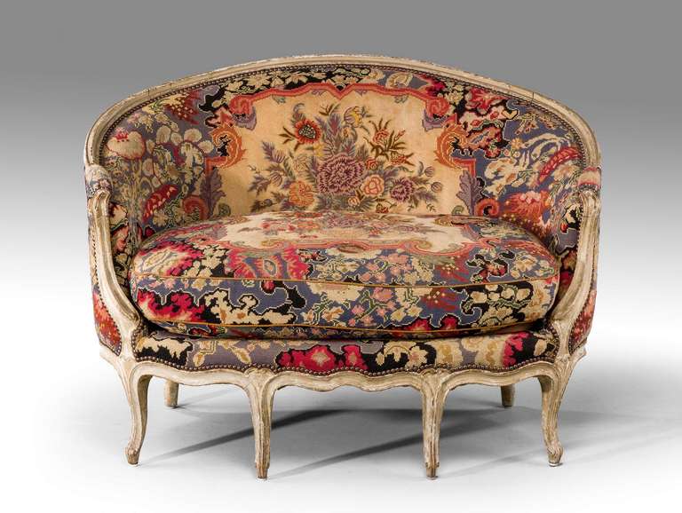 A very pretty canapé with a soft grey painted surface of Louis XV design but circa 1890, the tapestry work of exceptionally delicate form and in fairly good condition on well-shaped scroll supports.

RR.