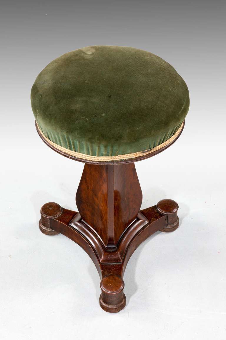 Regency period mahogany revolving and adjustable Stool, the trioform flared support over a well carved base terminating in roundels and clobbered circular feet.