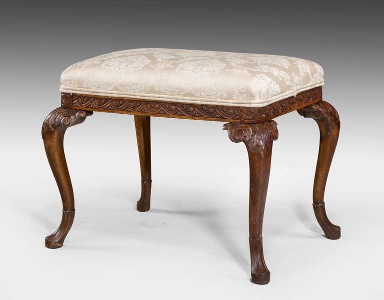 A walnut rectangle Stool on cabriole supports, the knees with acanthus leafs and scroll carving, the feet with formed lappets, vitruvian  scrolls to the styles with harebells.

RR