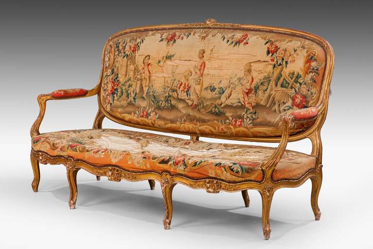 A substantial seven-piece French giltwood salon suite, overall in a somewhat tired and worn state, the upholstery, original, largely dates from the 18th century. It is not unusual to find earlier tapestries reused.

