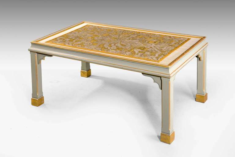 A fine low rectangular table, the central section with a panel of 18th century fabric executed in silver and gold thread.

RR.