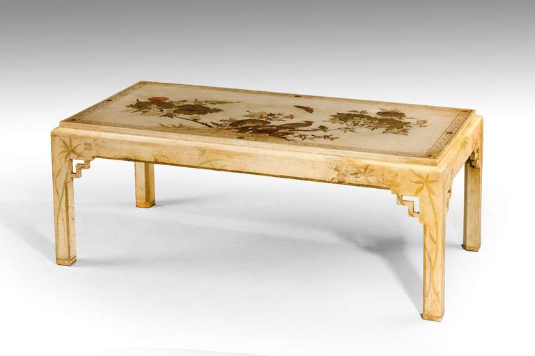 A mid-20th century low table of 18th century oriental design on four square supports with symmetrical corner blocks the top gilded and painted with oriental pheasants within a foliate and rocky landscape.
