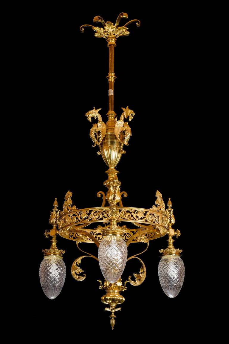 An elaborate gilt bronze chandelier with four cut-glass shades, the upper section with fantastic griffins and the main circular body delicately pierced with foliage and scrolls.

RR.