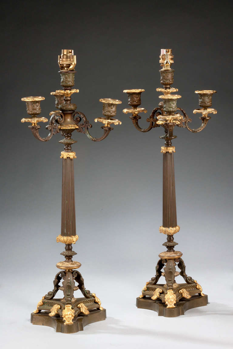 A pair of bronze and gilt bronze candelabra on tri form bases.