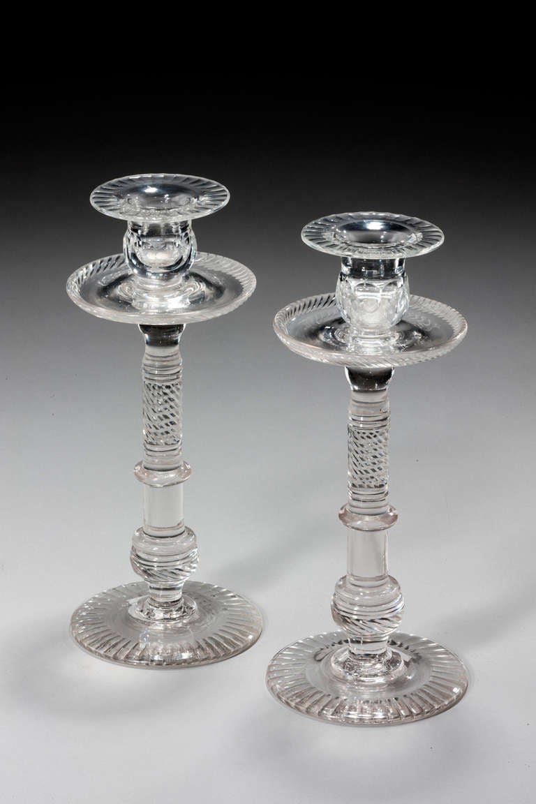 An unusually tall pair of glass candlesticks with writhen and turned sections to the stems.