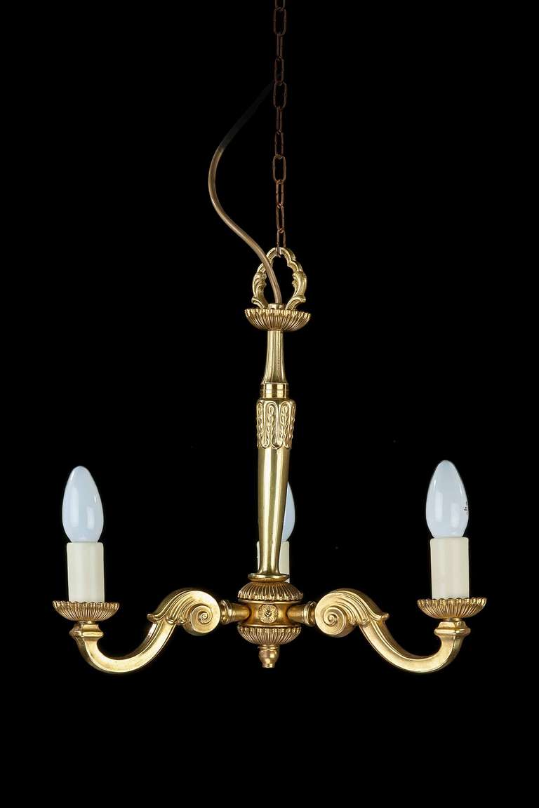 A small, three arm, cast brass Chandelier, scroll arms incorporating leafs and a turned and cast centre support.

RR