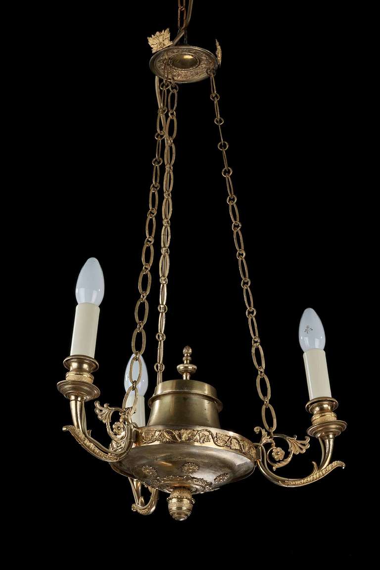 A good Restauration period gilt bronze, three-arm chandelier, the arms finely cast and chiseled, the circular centre with scroll decoration incorporating vine leafs, period cast chains in extremely good condition.

The earliest candle Chandeliers
